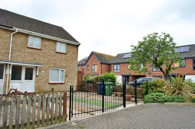 a fence in front of a house with houses at Tree View Apartment in Chesterton