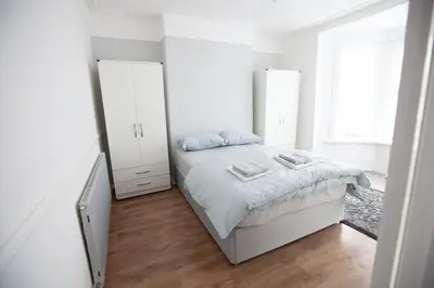 a white bedroom with a bed and a mirror at Beach palace in Clacton-on-Sea