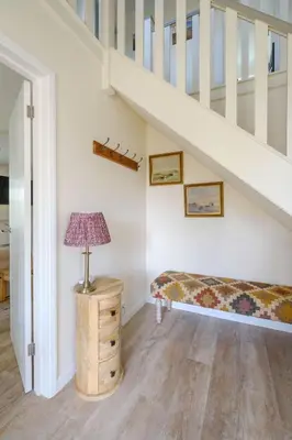 a room with a bed and a table with a lamp at 9 The Coastguards in Thorpeness
