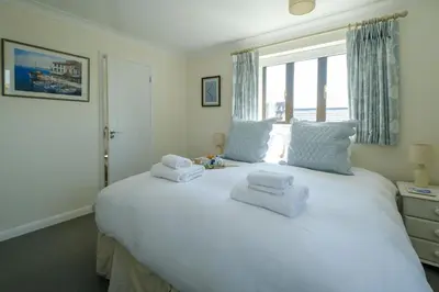 a bedroom with a large white bed with towels on it at 9 The Coastguards in Thorpeness