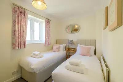 two twin beds in a room with a window at 9 The Coastguards in Thorpeness