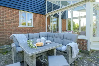 a patio with a blue couch and a table and chairs at 9 The Coastguards in Thorpeness