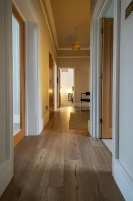 an empty hallway with wood flooring in a house at Stylish Central Apartment with Parking & Lift in Bury Saint Edmunds