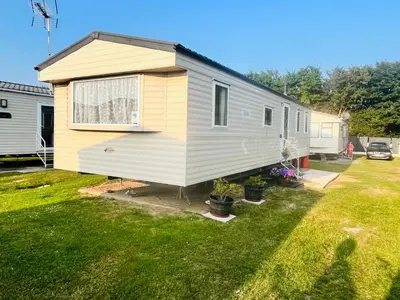 a yellow and white tiny house in a yard at Lola’s Caravan. Your home away from home. in Parkeston