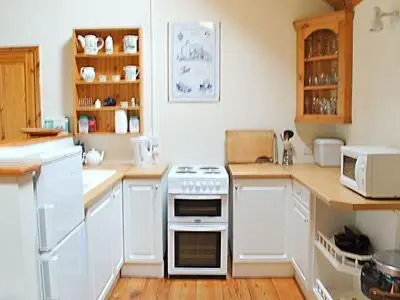 a kitchen with white cabinets and a stove top oven at Netherall Manor Lodge in Soham