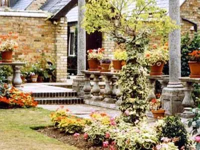 a house with a bunch of flowers in a yard at Netherall Manor Lodge in Soham