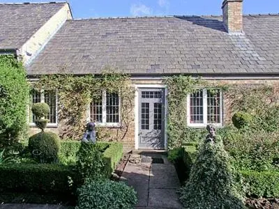 a brick house with a door and some bushes at Netherall Manor Lodge in Soham