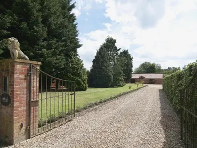 a gate with a dog statue on the side of a driveway at St Andrews Barn in Necton