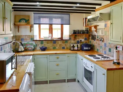 a kitchen with green cabinets and white appliances at The Cottage in Great Ellingham