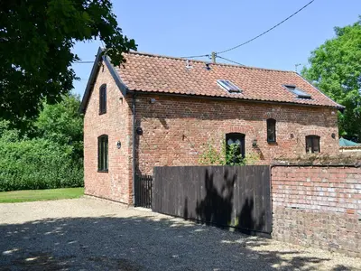 an old brick building with a wooden gate at The Cottage in Great Ellingham