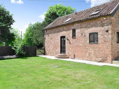 an old brick house with a grass yard at The Cottage in Great Ellingham