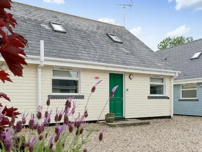 a white house with a green door and flowers at Jubileum Lodge Uk27999 in Watton