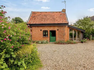 a brick house with a green door in a yard at The Old Bike Shop in Brockdish