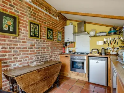 a kitchen with a brick wall and a wooden table at The Old Bike Shop in Brockdish