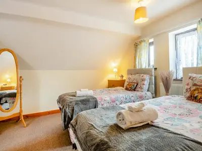 a bedroom with two beds and a mirror at Pear Tree Cottage in Banham