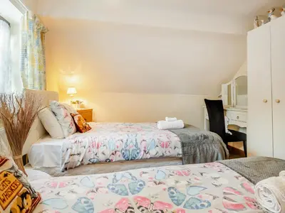 a bedroom with two beds and a chair and a window at Pear Tree Cottage in Banham