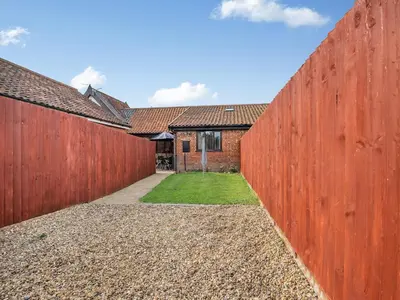 a large red fence in front of a house at Pear Tree Cottage in Banham