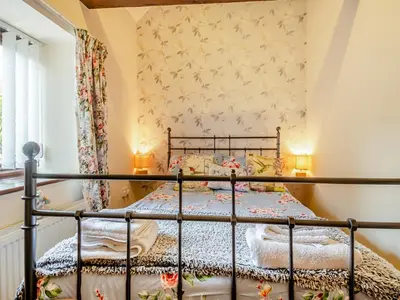 a bedroom with a metal bed in a room at Pear Tree Cottage in Banham