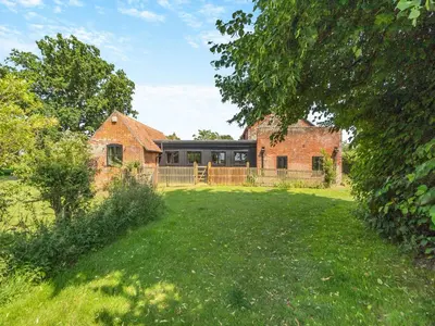 an old brick house with a fence and a yard at St Mary's Chapel in New Buckenham