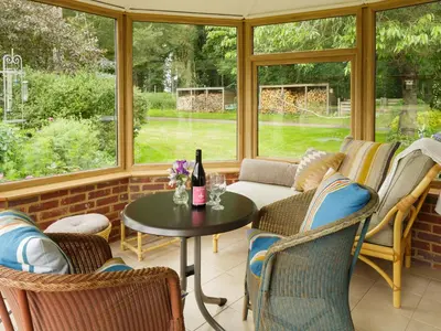 a screened in porch with a table and chairs at Covert Cottage in Gasthorpe