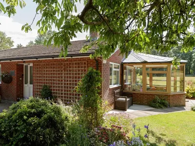 a red brick house with a large glass window at Covert Cottage in Gasthorpe