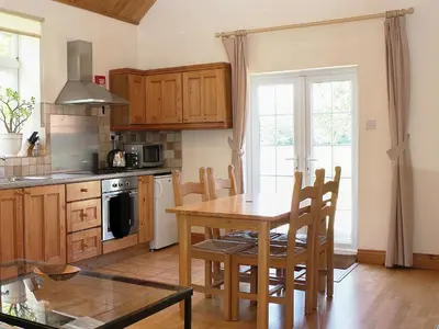 a kitchen with a wooden table and a dining room at Valley Farm Cottage in Sudbourne