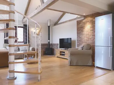 a living room with a staircase and a television at Barn Owl Cottage in Sudbourne