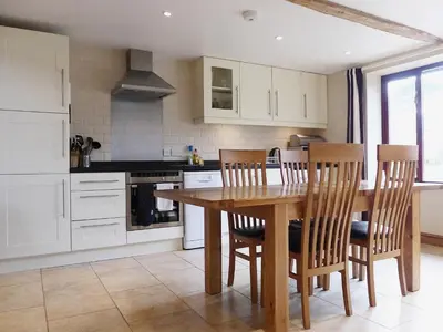 a kitchen with a wooden table and chairs at Barn Owl Cottage in Sudbourne
