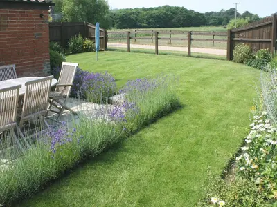 a garden with a table and chairs and purple flowers at Barn Owl Cottage in Sudbourne