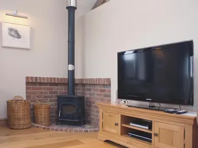 a flat screen tv sitting on top of a wood stove at Barn Owl Cottage in Sudbourne