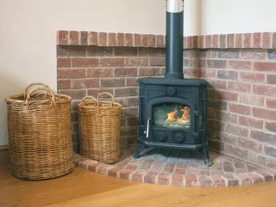 a fireplace with two baskets next to a brick wall at Barn Owl Cottage in Sudbourne