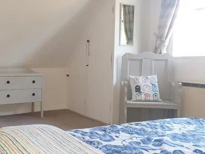 a bedroom with a bed and a dresser and a window at Three Ash Cottage in Bungay