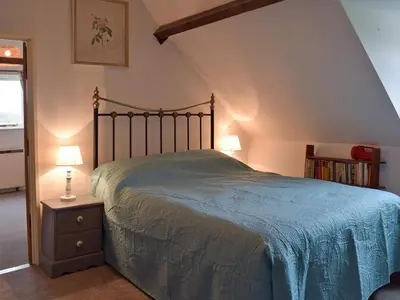 a bedroom with a bed and a book shelf at Three Ash Cottage in Bungay