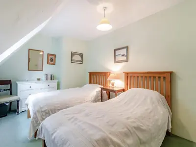 a bedroom with two beds and a table with a lamp at Oaklawn Cottage in Eye
