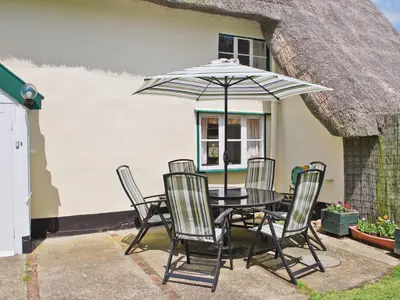 a table with chairs and an umbrella in front of a house at The Old House in Mellis
