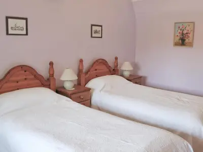 two beds in a bedroom with white sheets and lamps at The Old House in Mellis