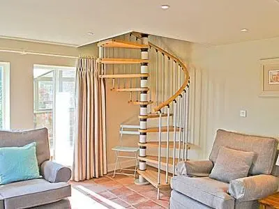 a living room with a spiral staircase and a couch at The Granary in Stuston
