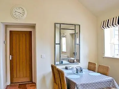 a dining room with a table and a clock on the wall at The Granary in Stuston