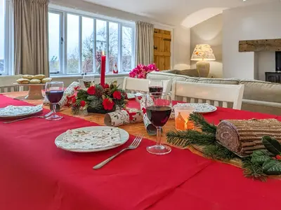 a dining room table with red table cloth and wine glasses at Dove Cottage in Halesworth