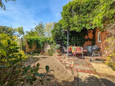 a backyard with a grill and a table and chairs at Dove Cottage in Halesworth