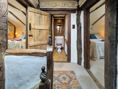 a bathroom with a toilet in a room with two beds at Stable End in Halesworth