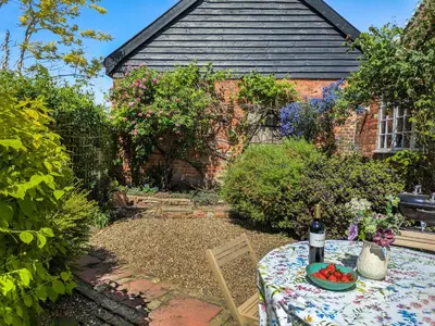 a garden with a table in front of a building at Stable End in Halesworth