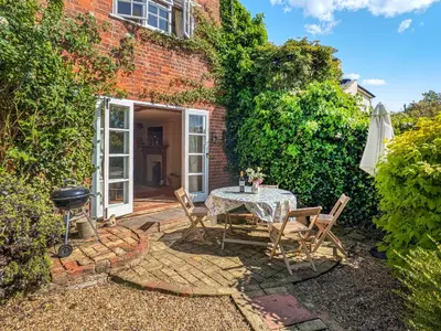 a patio with a table and chairs and an umbrella at Stable End in Halesworth