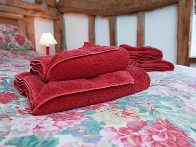 a pile of red towels sitting on a bed at Bell Corner Cottage in Cratfield