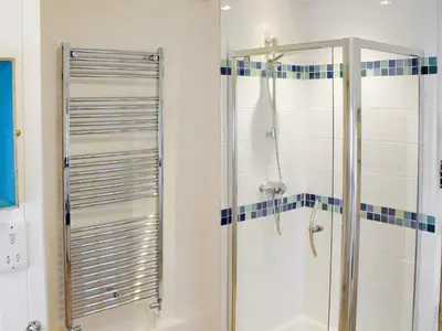 a bathroom with a shower with a glass door at Bell Corner Cottage in Cratfield