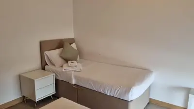 a small bedroom with a bed and a nightstand at Modern 2 bed flat with balcony in Southend-on-Sea