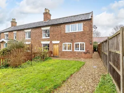 an exterior view of a brick house with a fence at Wheelwrights Cottage in Rumburgh
