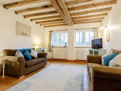 a living room with two couches and a tv at Wheelwrights Cottage in Rumburgh