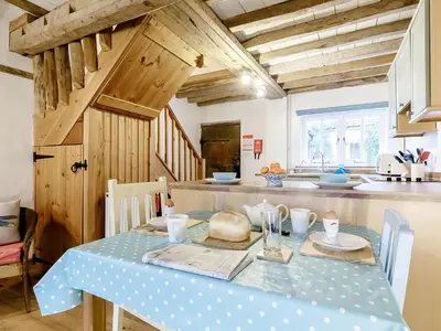 a kitchen with a table with a blue table cloth on it at Wheelwrights Cottage in Rumburgh