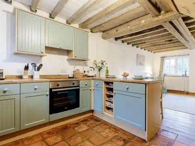 a kitchen with green cabinets and a wooden floor at Wheelwrights Cottage in Rumburgh